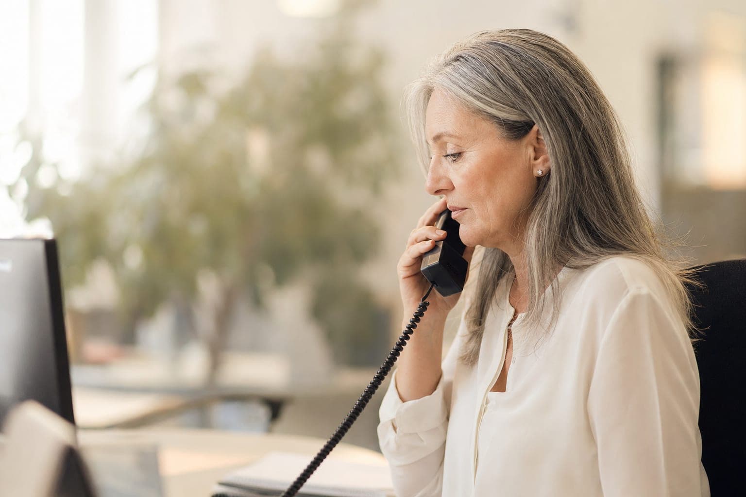 Mitarbeiterin im Telefonat am Schreibtisch, bereit für Ihr Erstgespräch